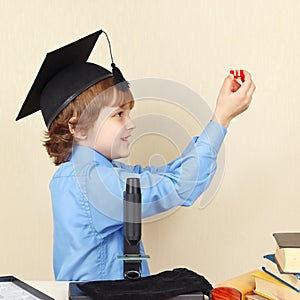 Little professor in academic hat conducts research with microscope