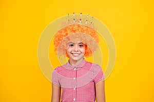 Little queen in wig wearing golden crown. Teenage girl princess holding crown tiara. Prom party, childhood concept.