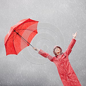 A little rain wont dampen my mood. A beautiful young woman standing outside with her red umbrella.