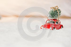 Little red car toy carrying Christmas tree