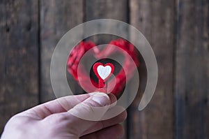 Little red clothespins hearts in hand on a background of a big heart. Love