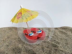 Little Red flip flops under an umbrella on beach sand