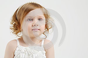 Little red hair girl in white dress looks up on