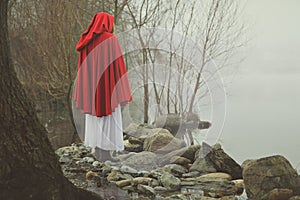 Little red riding hood on a shore of a misty lake