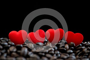 Little red satin hearts on coffee beans isolated on black background, valentines day or wedding day celebrate