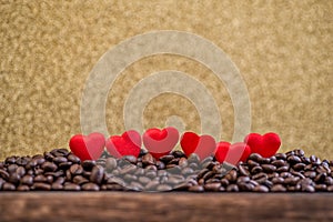 Little red satin hearts with letters on coffee beans with gold background, valentines day or wedding day celebrating