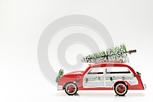 Little red vintage car carrying a Christmas tree on top