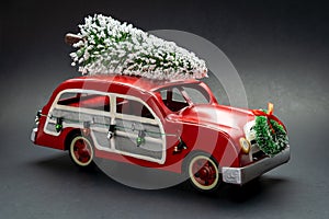 Little red vintage car carrying a Christmas tree on top