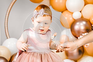 Little redhead baby girl celebrates first birthday anniversary. 1 year family baloons party. Professional photoshoot