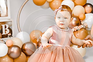 Little redhead baby girl celebrates first birthday anniversary. 1 year family baloons party. Professional photoshoot