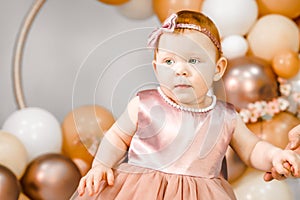 Little redhead baby girl celebrates first birthday anniversary. 1 year family baloons party. Professional photoshoot