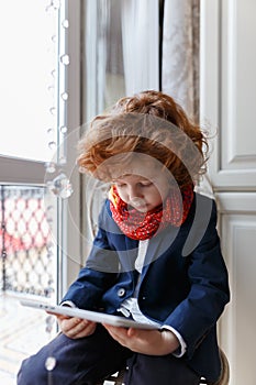 Little redhead boy uses a tablet PC