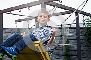 Little redheaded boy is swinging on the seesaw