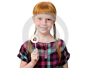 Little redheaded girl holding a candy with a cherry