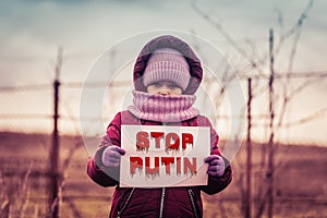 Little refugee girl with a sad look and a poster with the inscription stop putin. Social problem of refugees and internally photo
