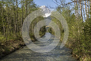 Little river with trees on both sides and a mountain top with sn