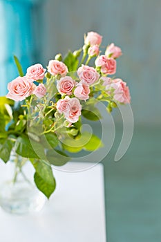 Little rose flowers on a white wooden table