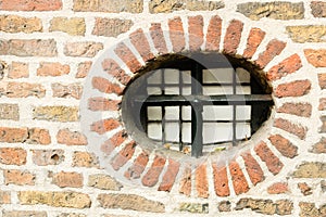 Little round window with cast iron fence in ancient brick wall, Utrecht, the Netherlands