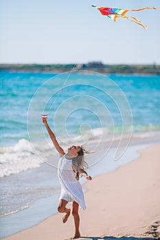 Little girl flying a kite on beach at sunset
