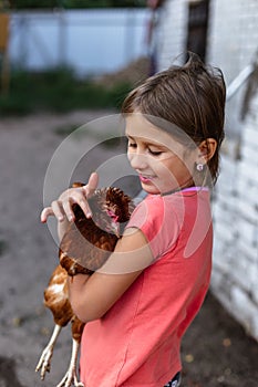 Little rural girl with chicken in her arms