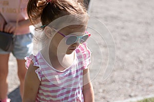 Little sad beautiful girl in sunglasses with pigtails on a walk