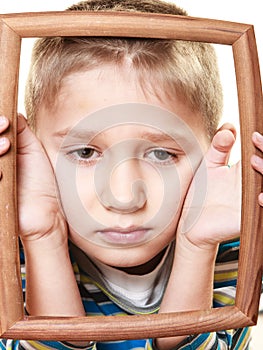 Little sad boy child framing his face