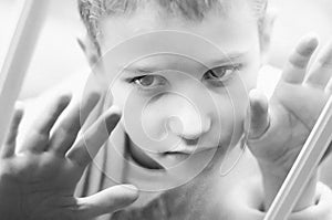 Little sad boy looks out the window. Black and white photo of a close-up child. Hungry child with big clear eyes eating bread