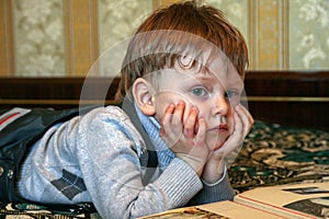 A little sad boy lying on the bed and watching TV, blur and grain effect.