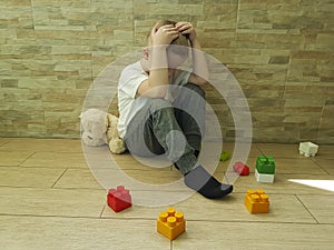 Little sad boy sitting on the floor expression tenderness unhappy a block depression frustratedsadness