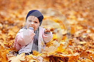 Little sad girl in the autumn park