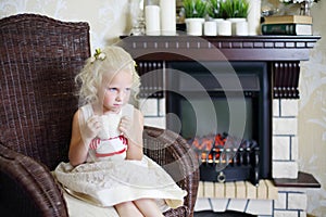 Little sad girl sits in wicker rocking chair with