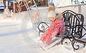 Little sad girl sitting on a bench in the skating