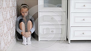 Little sad girl sitting on the floor