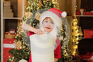 Little Santa Claus helper with Christmas gift. Cheerful cute child opening a Christmas present.