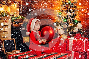 Little Santa Claus helper elf with a huge decorational ball for Christmas tree. Christmas attributes. Merry and bright