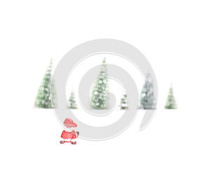 Little Santa Claus toy sitting in the snow in front of a row of pine trees