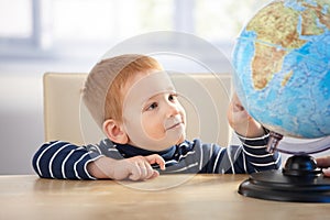 Little scholar studying globe smiling