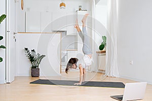 Girl staying in shape, walking on hands at home during isolation