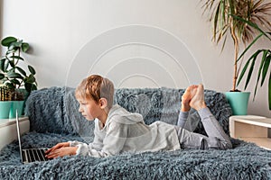 Little school boy having video call, online class on laptop during covid quarantine lockdown