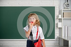 Little school boy student eating apple learning in class, study english language at school. Genius child, knowledge day.