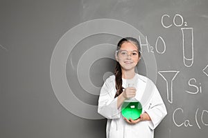 Little school child in laboratory uniform with flask