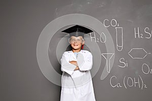 Little school child in laboratory uniform with graduate cap