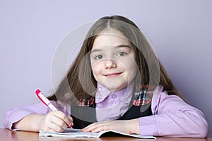 Little school girl doing homeworks at desk