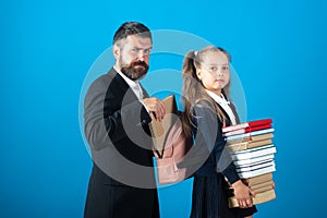 Little school girl hold big stack school textbook notebook books. Father teacher helping to pupil, preparing backpack