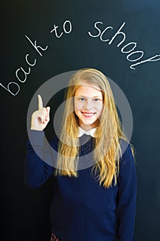 little school girl near school blackboard