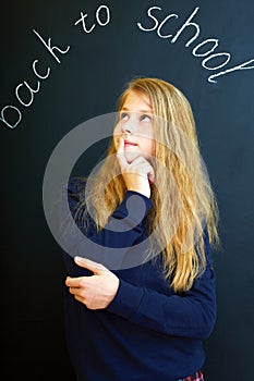 little school girl near school blackboard