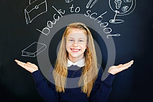 Little school girl near school blackboard