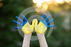 Little school girl showing hands painted in yellow and blue color. Kid hands painted in blue and yellow flag of Ukraine