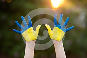 Little school girl showing hands painted in yellow and blue color. Kid hands painted in blue and yellow flag of Ukraine