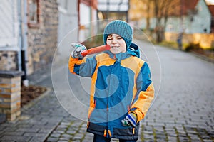 Little school kid boy of elementary class walking to school on cold winter day. Happy child having fun on a city street